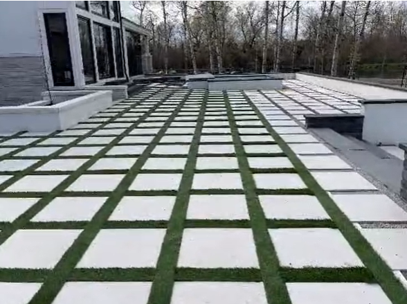 Modern patio with large square pavers and artificial turf grid strips by Rosales Landscaping